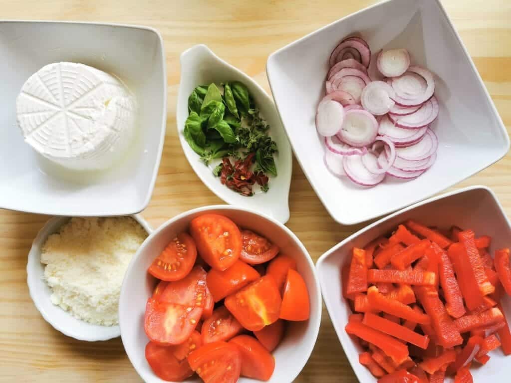 chopped tomatoes, red peppers, onions and herbs in white bowls plus ricotta and grated pecorino in white bowls