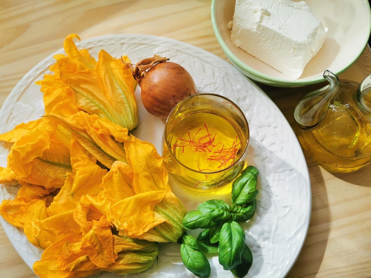 Ingredients for pasta with zucchini flowers on a wooden table.