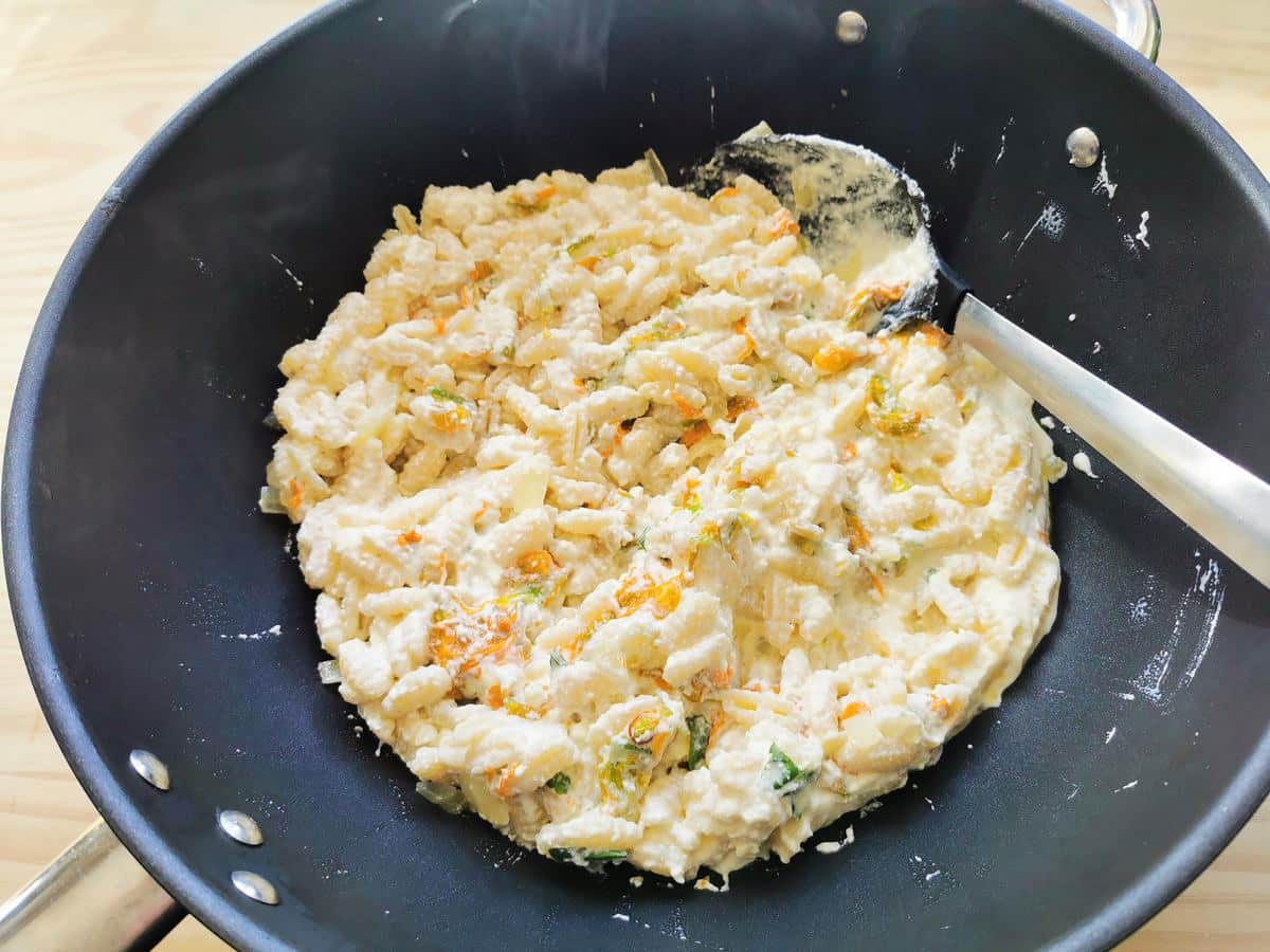 Mixing the pasta with the ricotta sauce in a pan.