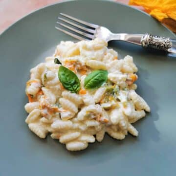 Pasta with zucchini flowers, ricotta and saffron on a plate.