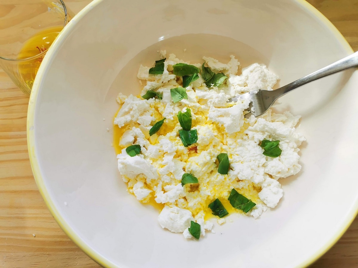 Mixing ricotta cheese, chopped basil, saffron, olive oil and black pepper in a bowl.