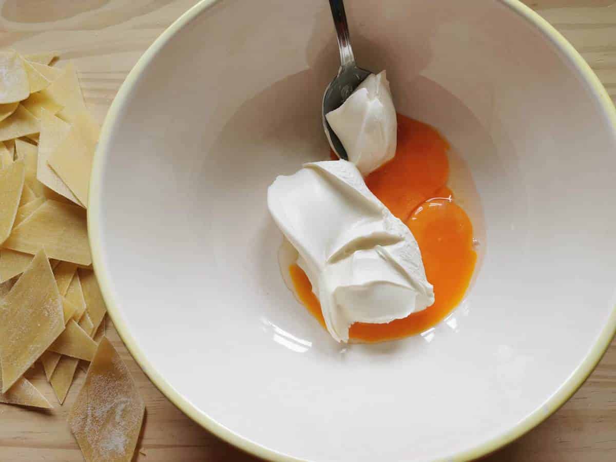 Egg yolks and mascarpone in large white bowl.