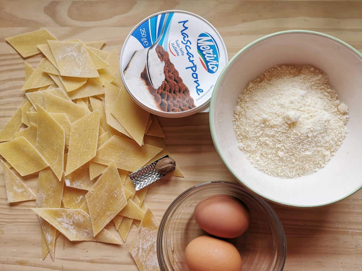 Ingredients to make maltagliati with mascarpone on wood work surface.