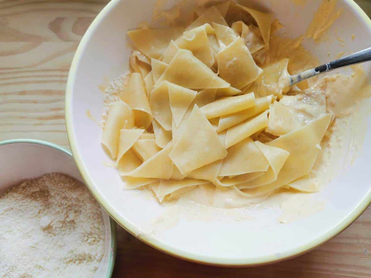 Cooked maltagliati pasta with mascarpone cream in white bowl.