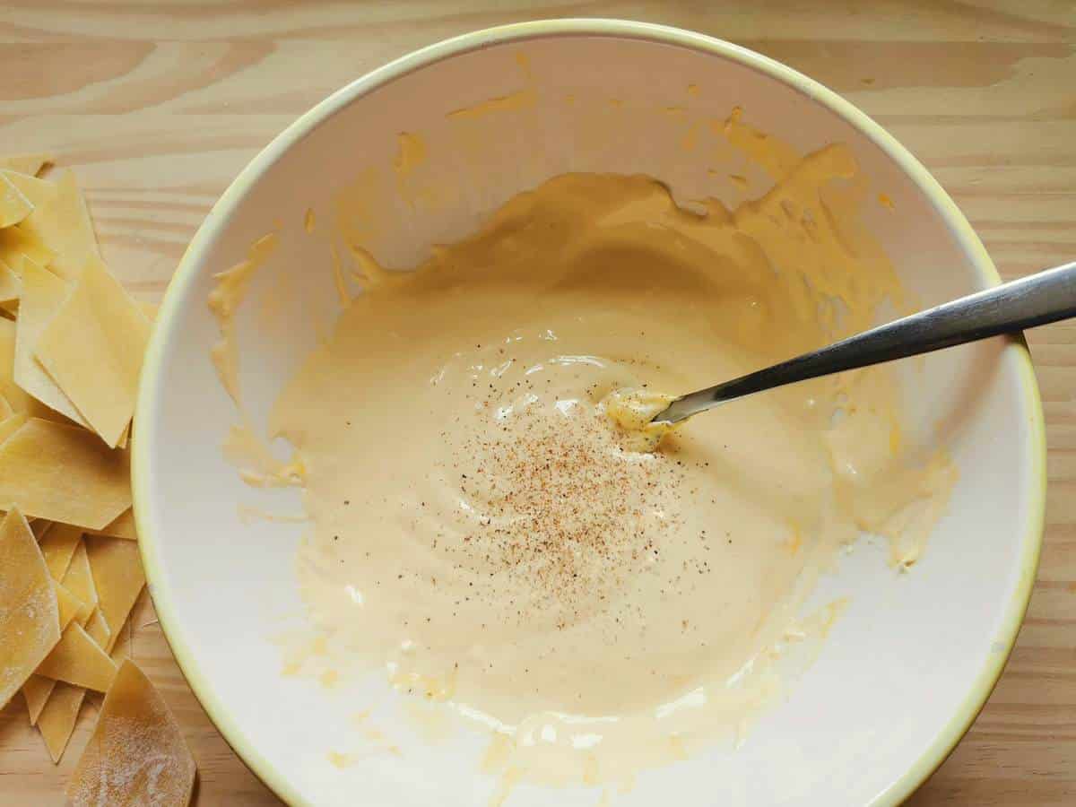 Egg yolks and mascarpone cream with added grated nutmeg in white bowl.