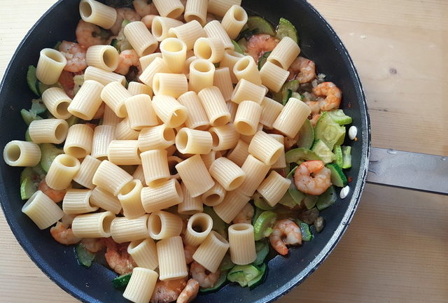 mezze maniche pasta in frying pan with zucchini and prawns