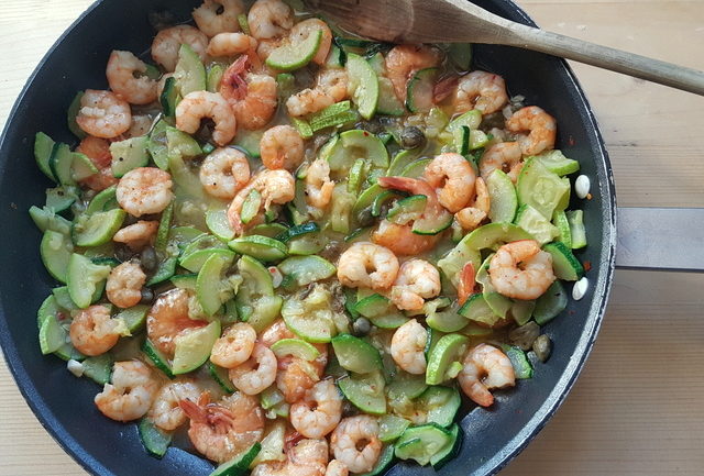 zucchini, capers and prawns cooking in frying pan