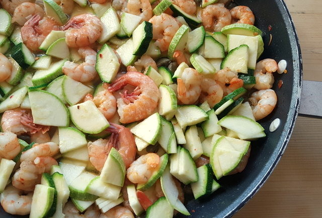 uncooked zucchini slices in frying pan with prawns