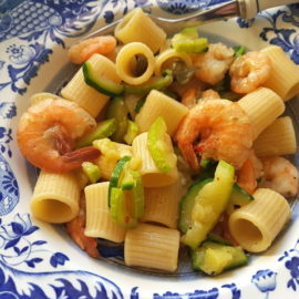 mezze maniche pasta with zucchini and prawns in blue and white plate