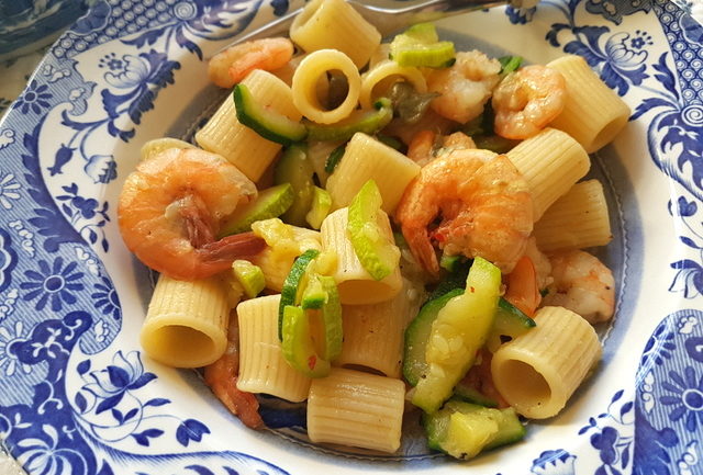 mezze maniche pasta with zucchini and prawns in blue and white plate