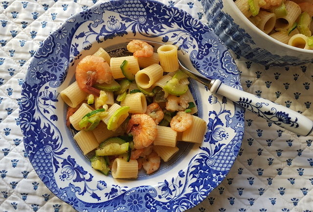 mezze maniche pasta with zucchini and prawns in blue and white plate