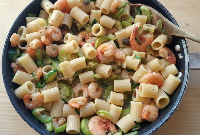 mezze maniche pasta with zucchini and prawns in pan