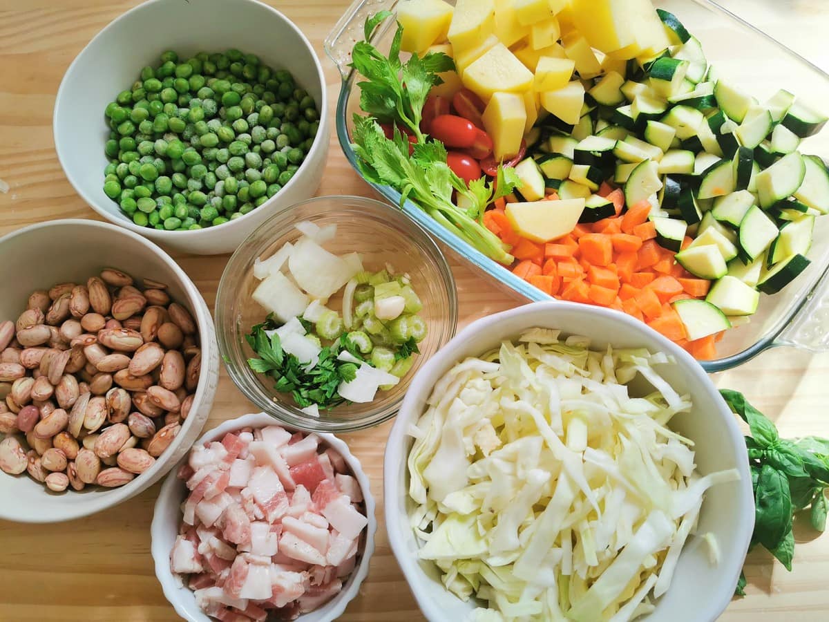 Prepared ngredients for minestrone Milanese displayed in different bowls. 