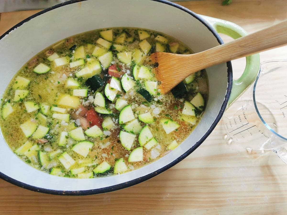 Vegetables and beans covered with water in Dutch oven.