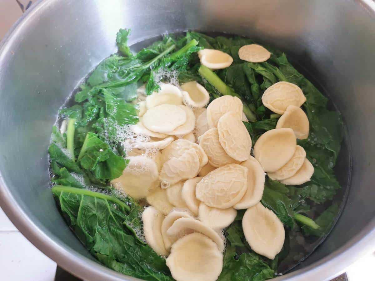 Broccoli rabe and orecchiette cooking in a pot of boiling water.