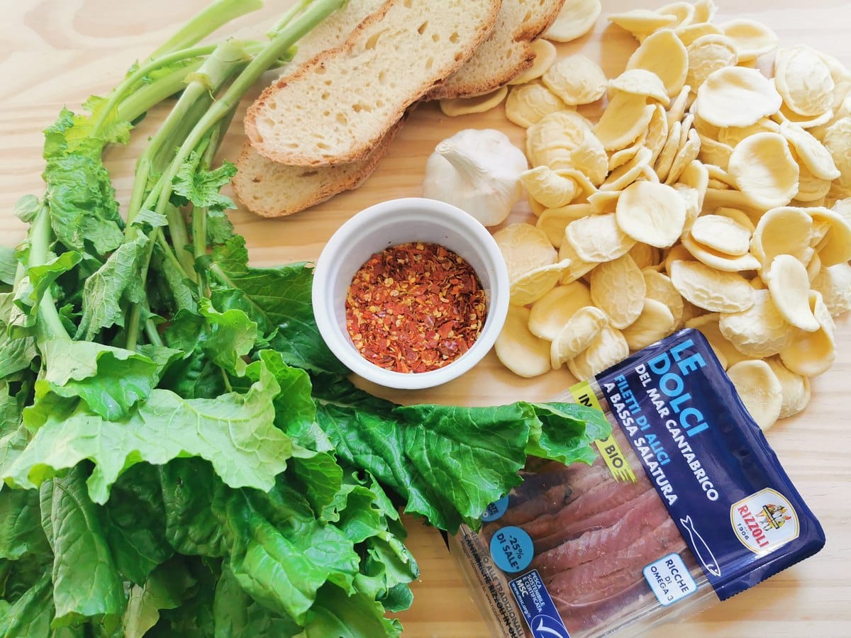 Orecchiette, broccoli rabe, anchovy fillets, garlic, bread and dried peperoncino on a kitchen counter