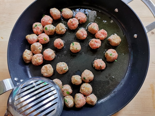 meatballs cooking in olive oil in skillet