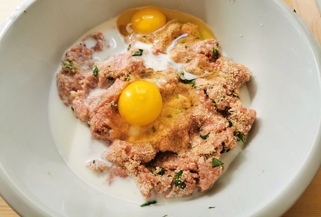 ground meat mixture with eggs and milk in white bowl