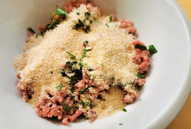 ground beef and pork, breadcrumbs, grated cheese and parsley in white bowl