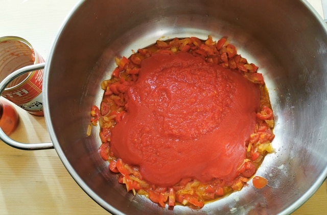 tomato passata added to onions and small tomatoes in large pot