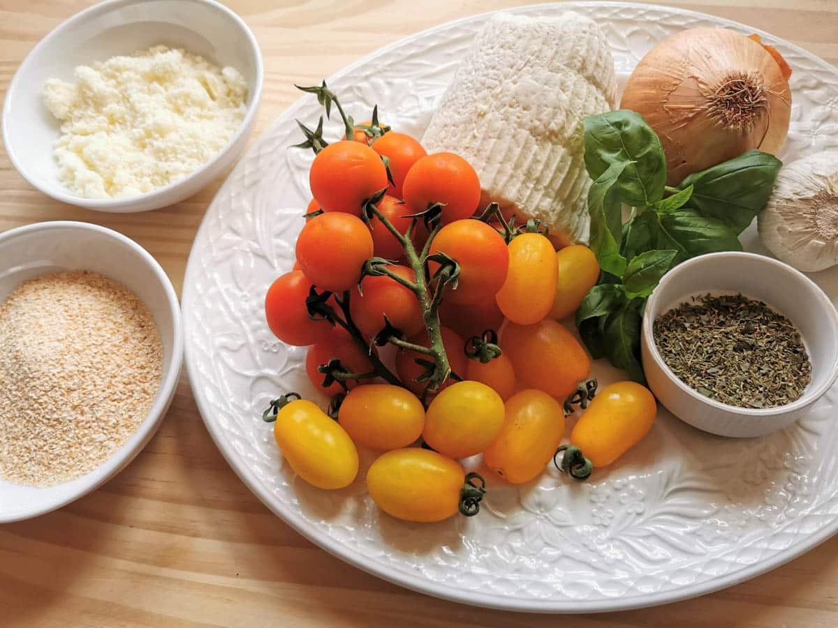 Ingredients for roasted tomato pasta. Which includes red and yellow cherry tomatoes, pasta, garlic, fresh basil, oregano, onion, breadcrumbs, Pecorino Romano, ricotta salata.