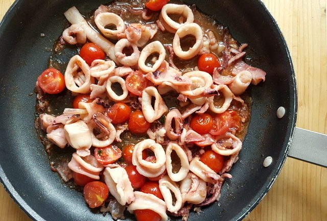 calamari and cherry tomatoes cooking in frying pan