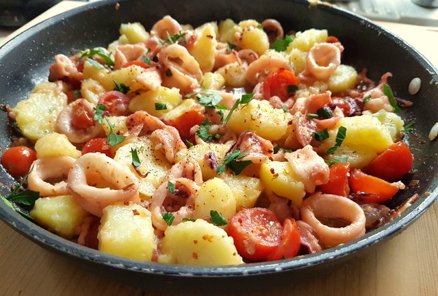 calamari, potatoes and cherry tomatoes in frying pan