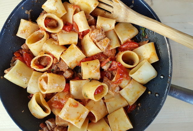 organic mezzi paccheri pasta mixed with fresh tuna ragu in skillet