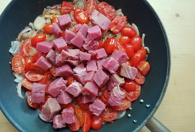 sliced onions, halved date tomatoes and cubed fresh tuna in skillet