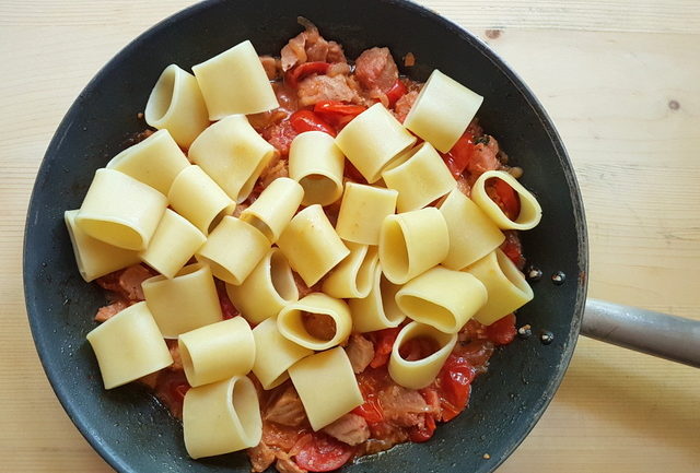 cooked organic mezzi paccheri added to sauce in skillet