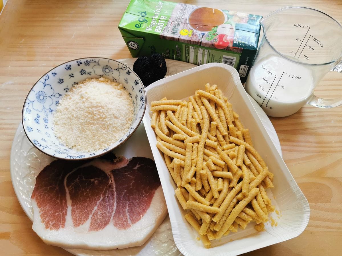 Ingredients for passatelli with proscuitto and parmigiano cream on wood worktop.