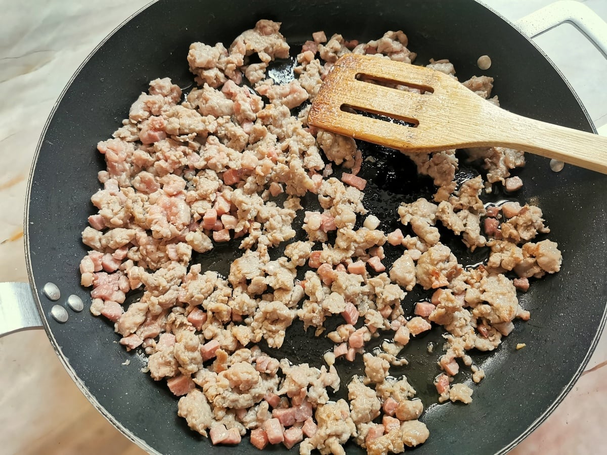 Browned sausage meat and pancetta in skillet.