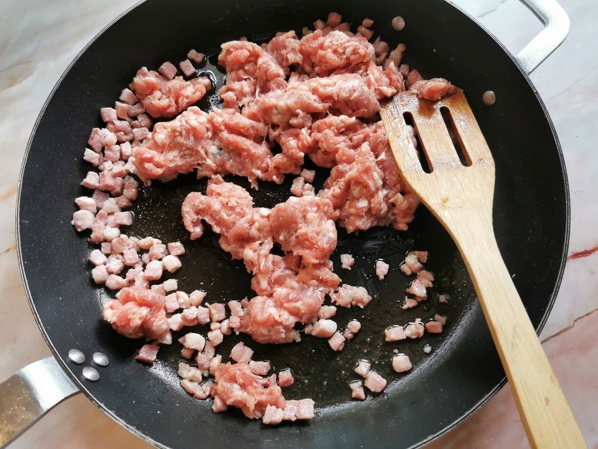 Pancetta cubes and sausage meat in skillet.