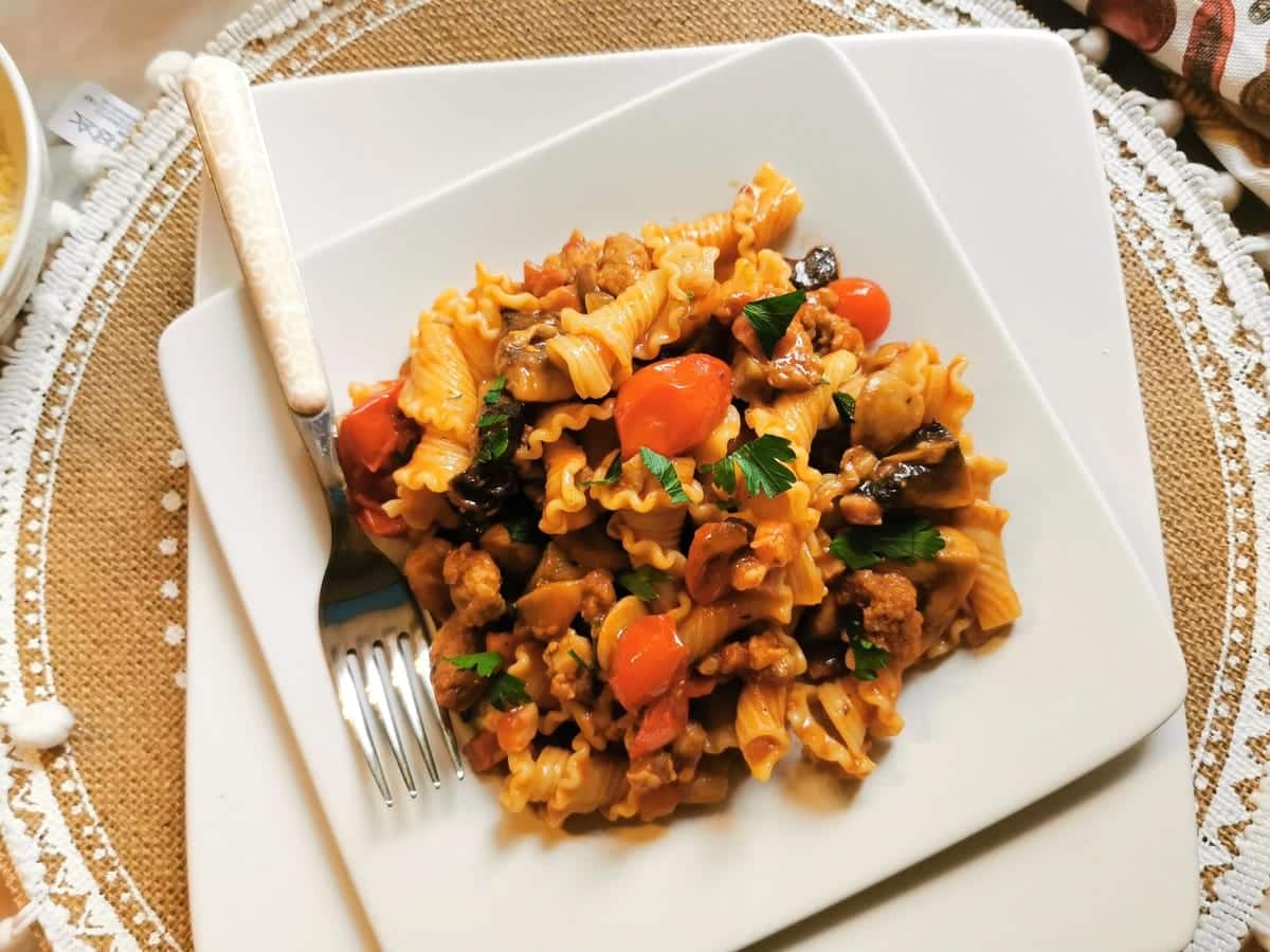 A sering of pasta alla Boscaiola on a square white plate.