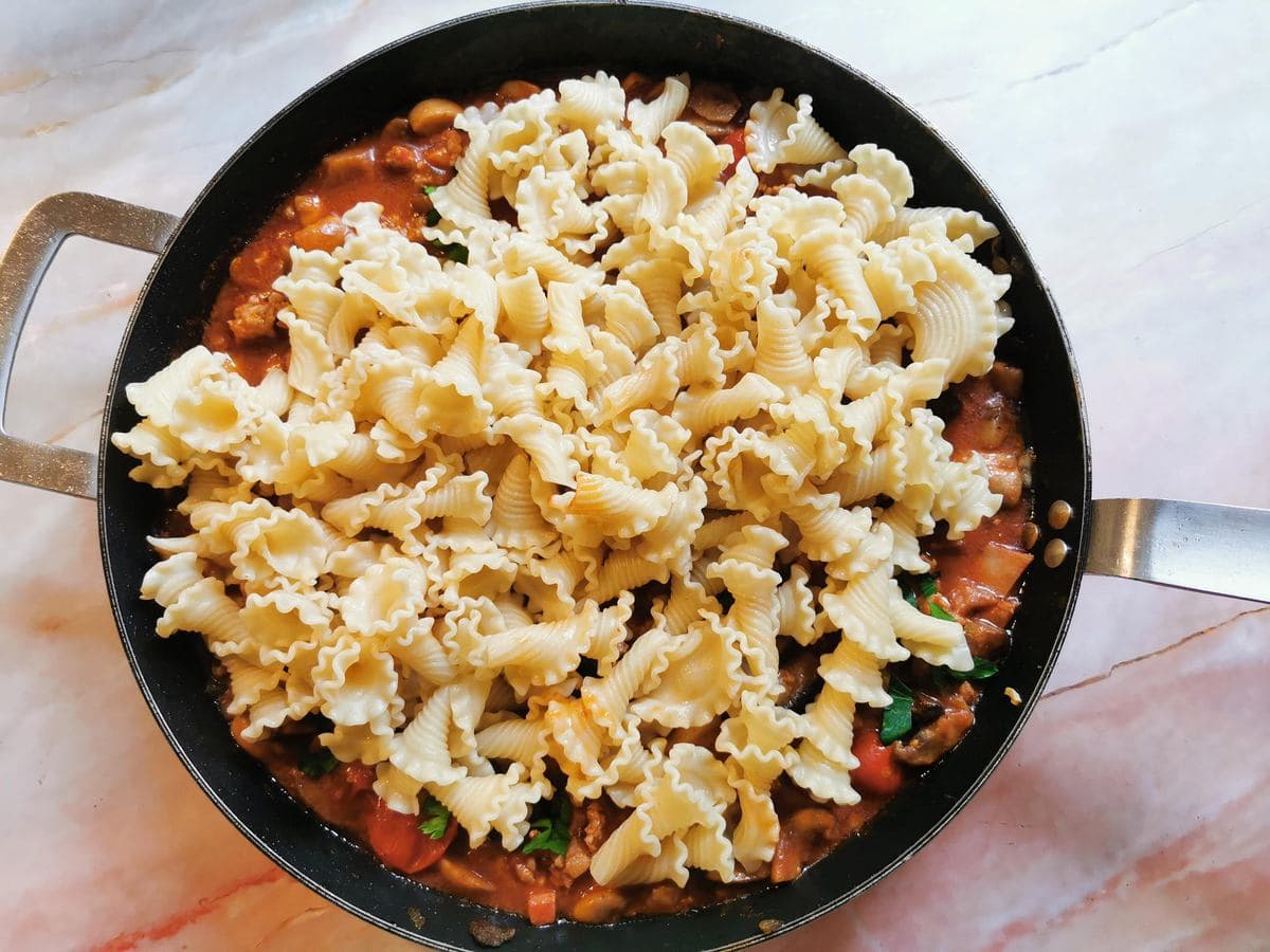 Cooked pasta in skillet with boscaiola sauce.