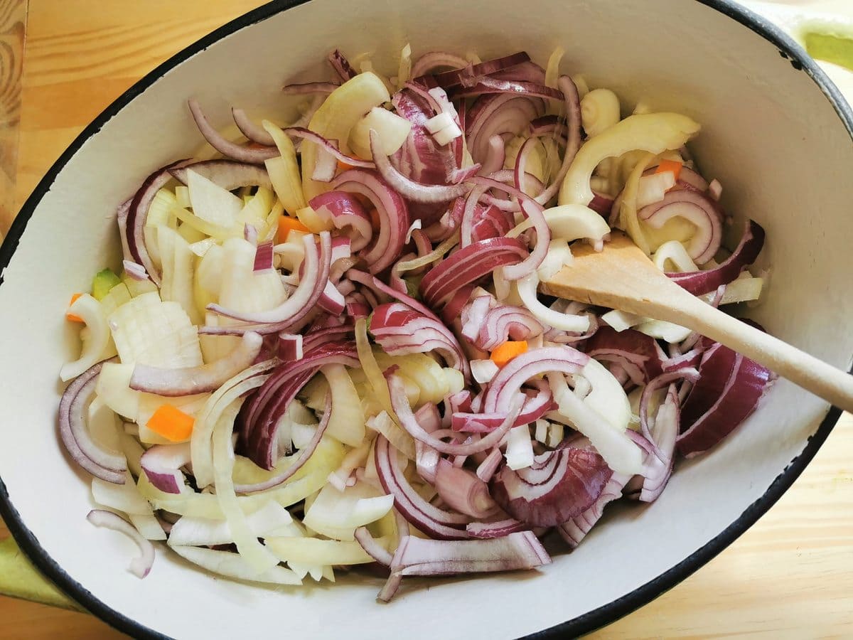 Sliced onions added to carrots and celery in Dutch oven.