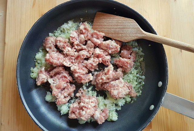 crumbled sausage and chopped onion in frying pan