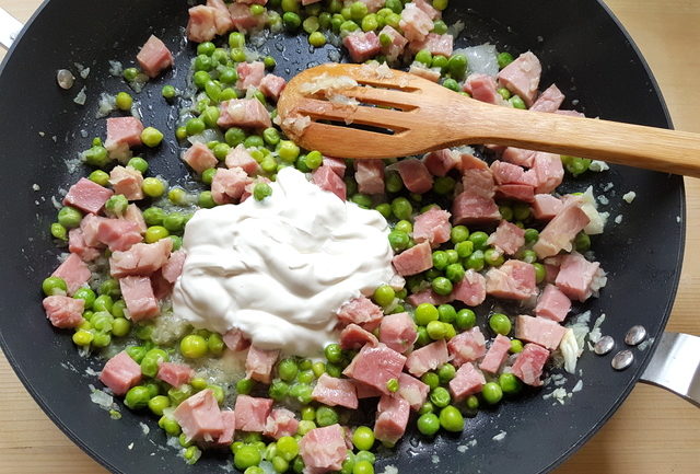 chopped ham, chopped onion, fresh peas and heavy cream in frying pan