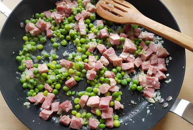 chopped ham, chopped onions and fresh peas in frying pan