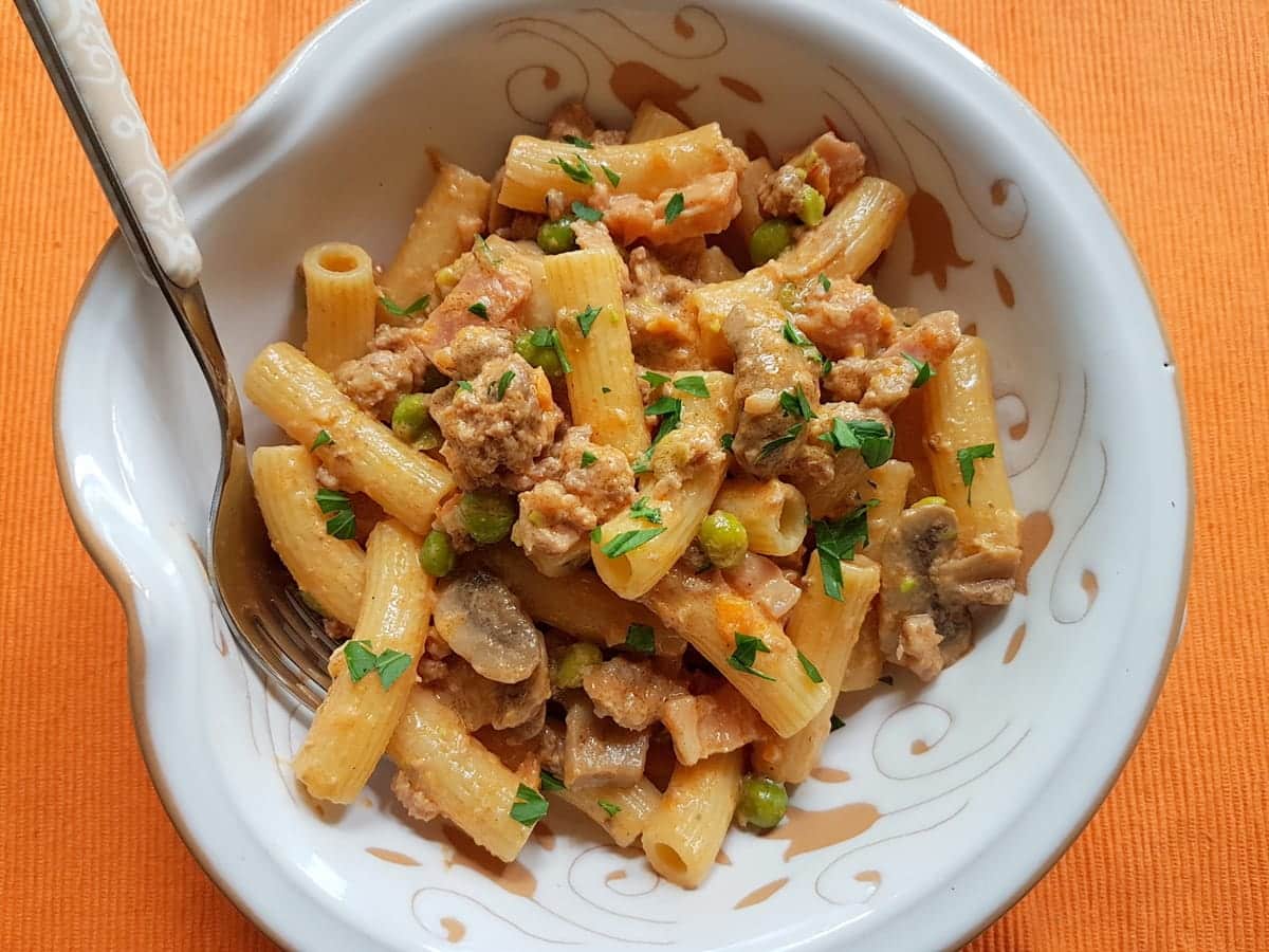 Pasta alla pastora in white bowl on orange place mat.