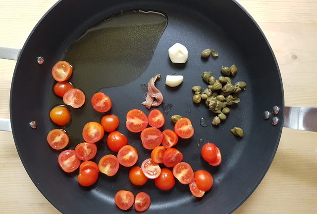 cherry tomato halves, anchovies, garlic and capers in frying pan