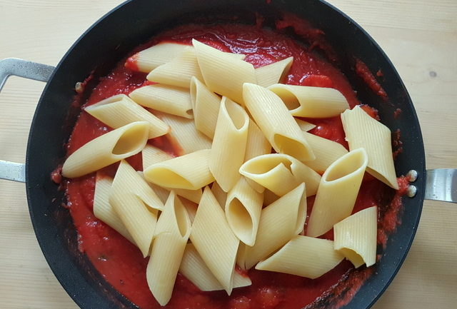 pennoni pasta in sauce in frying pan