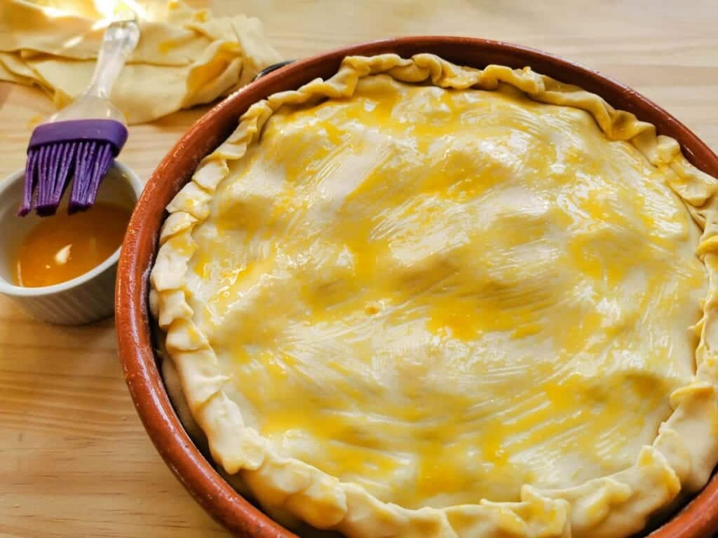 shortcrust pastry sheet brushed with egg yolk covering the top of the pie.