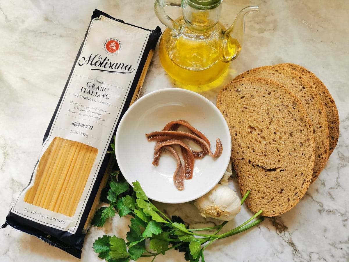 Ingredients for pasta with breadcrumbs on marble worktop.