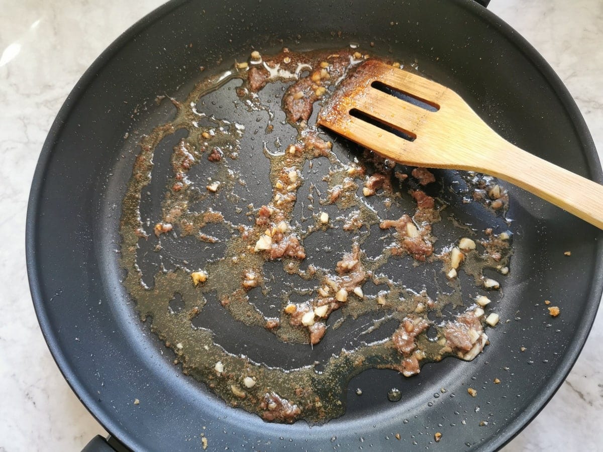 Pieces of anchovie and chopped garlic cooked in olive oil in skillet.