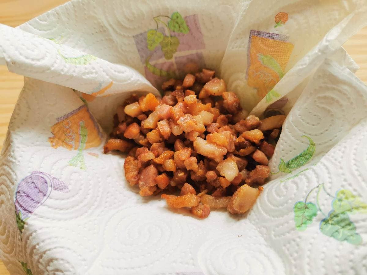 Crispy pancetta cubes in bowl with kitchen paper.
