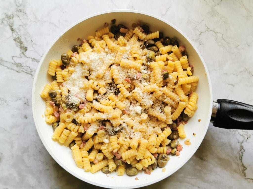 pasta and fava beans sauce with grated pecorino in pan