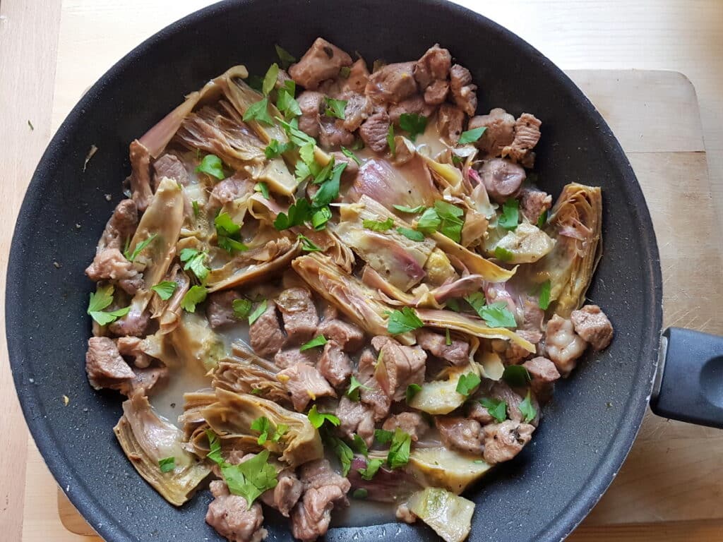 cooked lamb and artichokes with parsley in skillet