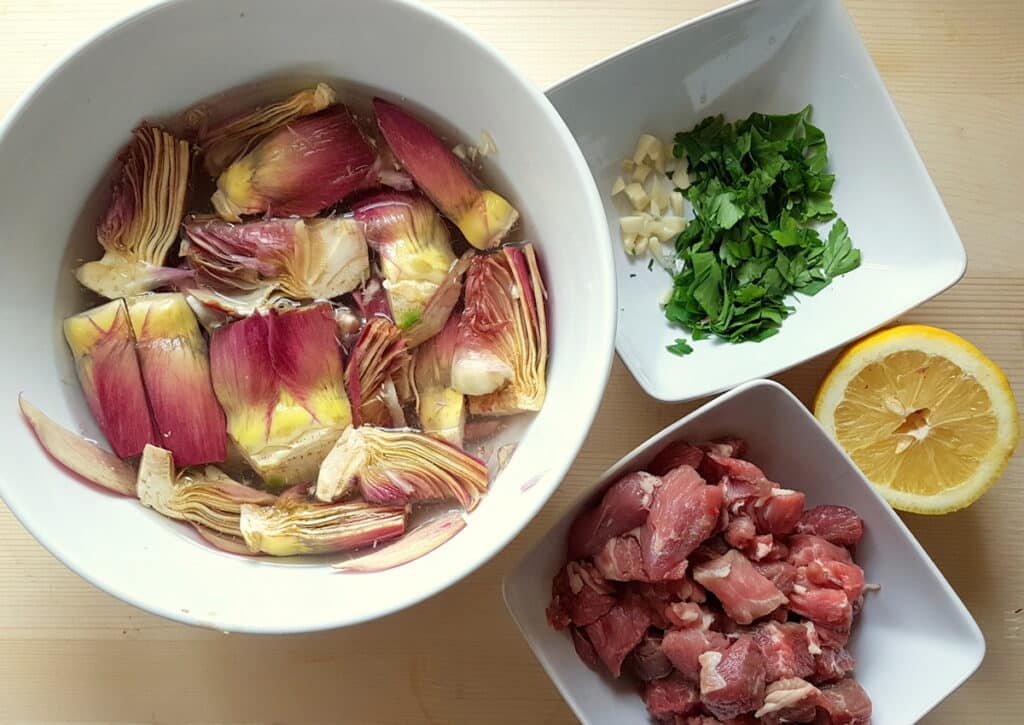 ingredients for lamb and artichoke ragu prepared in white bowls