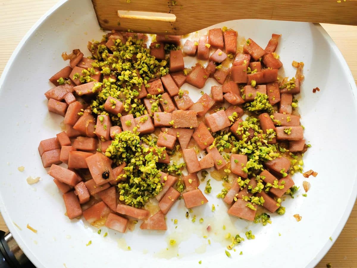 pistachio granules added to pan with mortadella